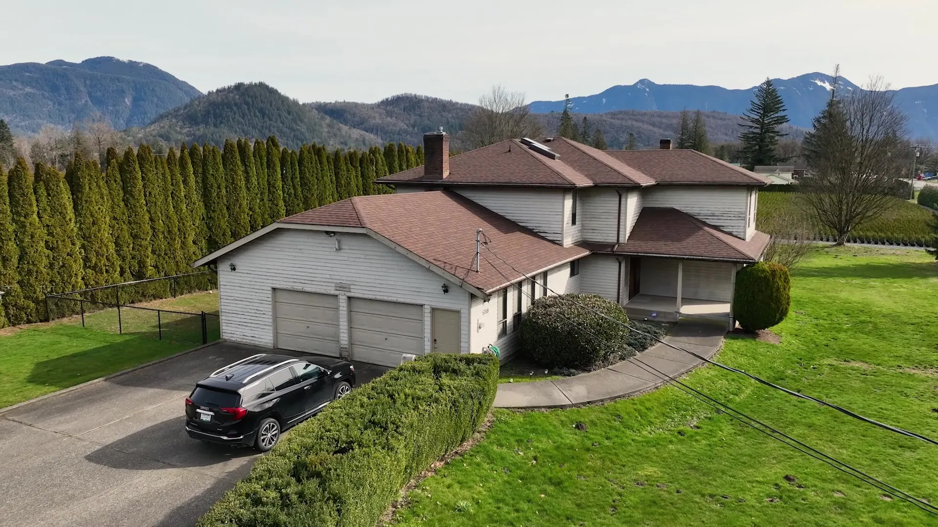 Aerial view of the finished home with light-grey siding and a landscaped front