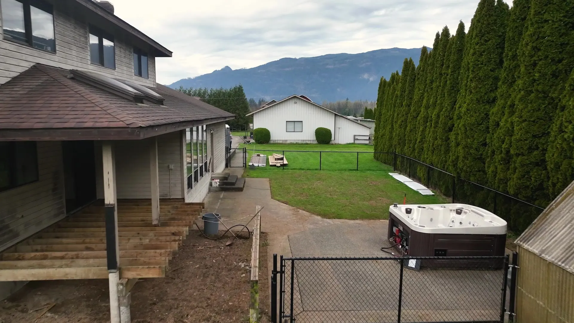 Back of the home with a covered deck and hot tub after the exterior renovation