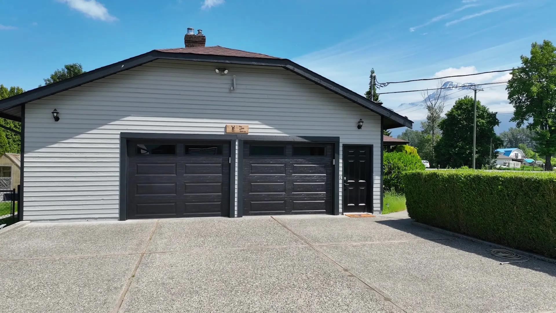 The refreshed garage with bold black woodgrain doors against light-grey siding