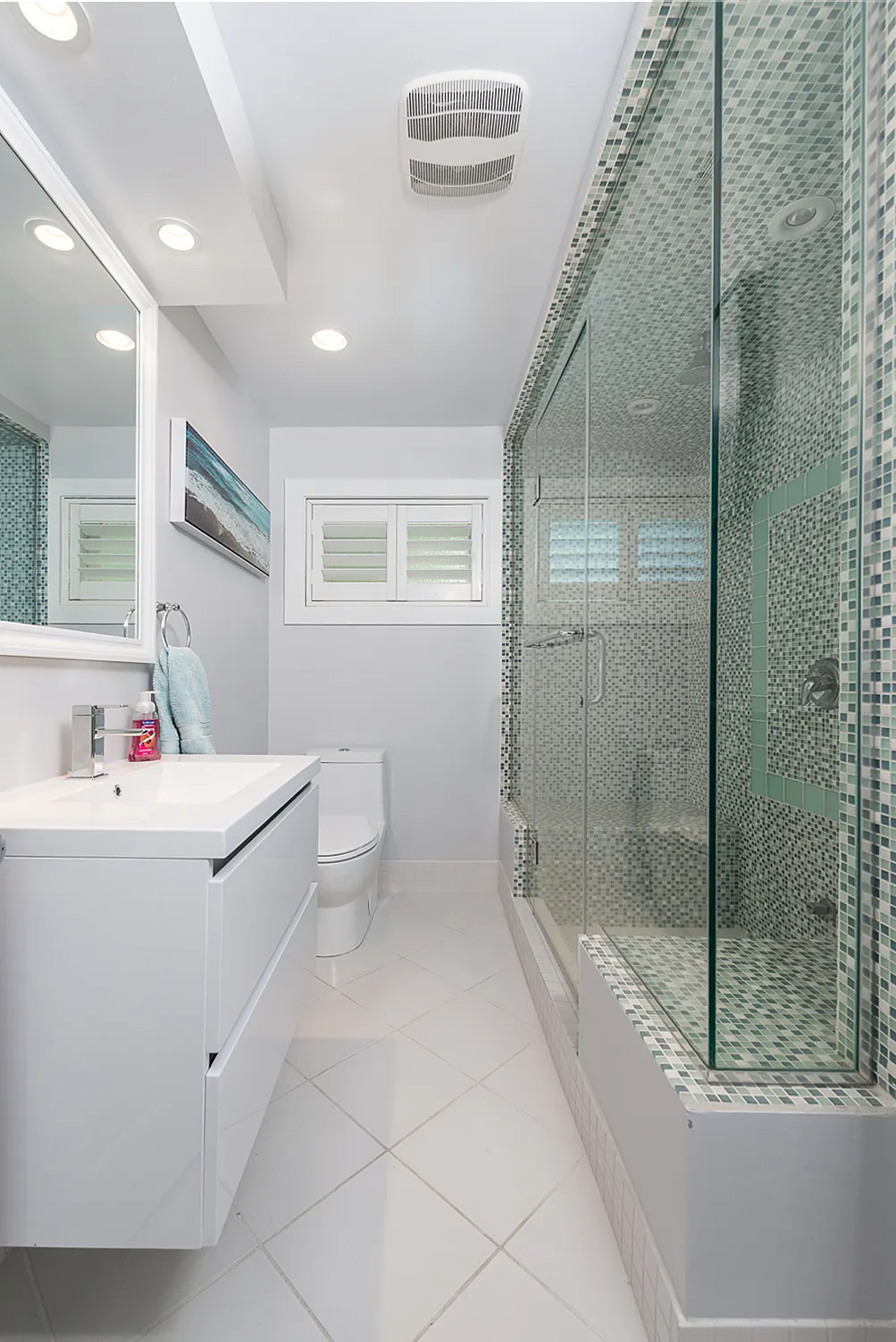 Bright main bathroom with a glass shower, mosaic accent tile, and a white vanity