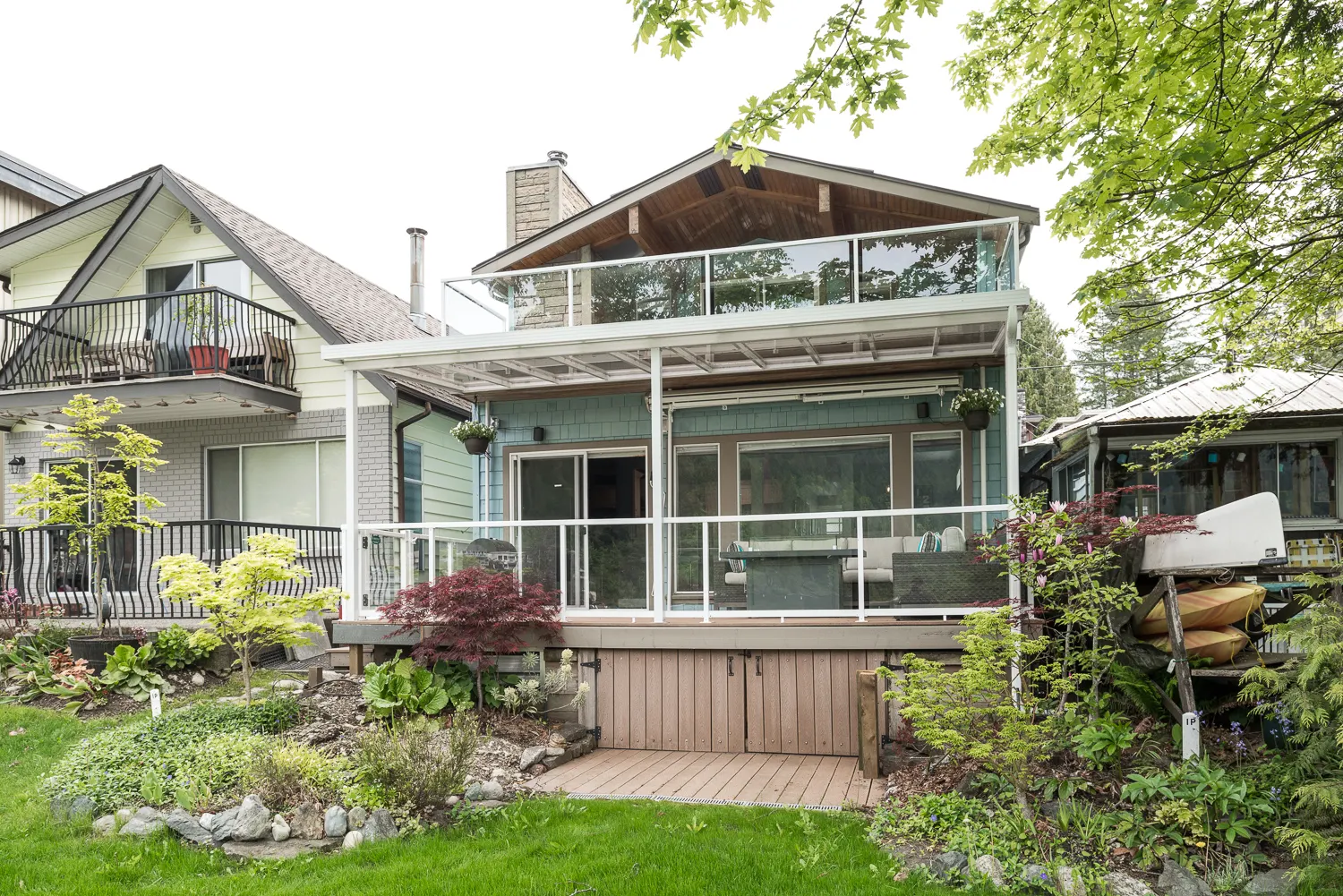 Rear exterior of the finished lakefront home with multi-level decks and mature landscaping