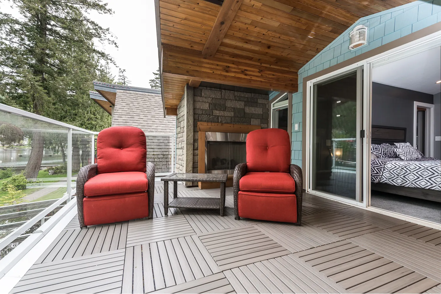 Lakeside deck with red lounge chairs under a cedar-toned ceiling, overlooking Cultus Lake