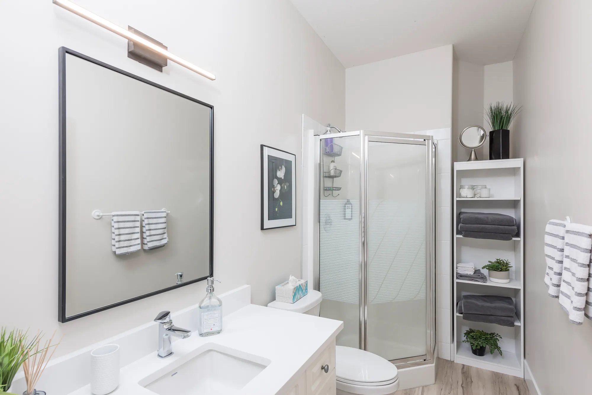 The rebuilt bathroom, bright and clean with a glass shower, framed mirror, and modern vanity