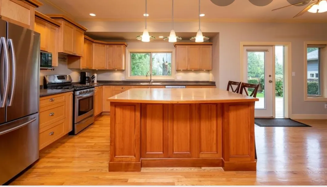 The original kitchen with honey-oak cabinets, a large oak island, and dated appliances