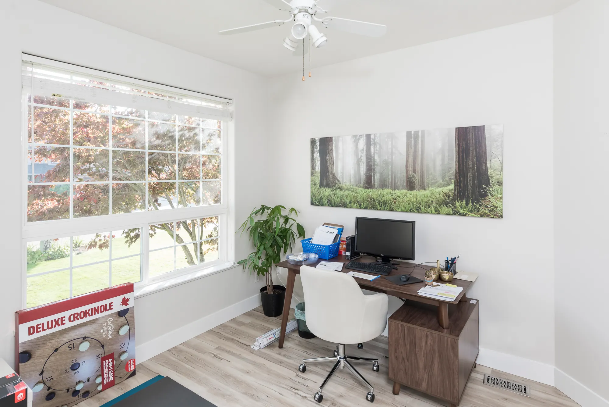 Bright home office with a large picture window and forest artwork