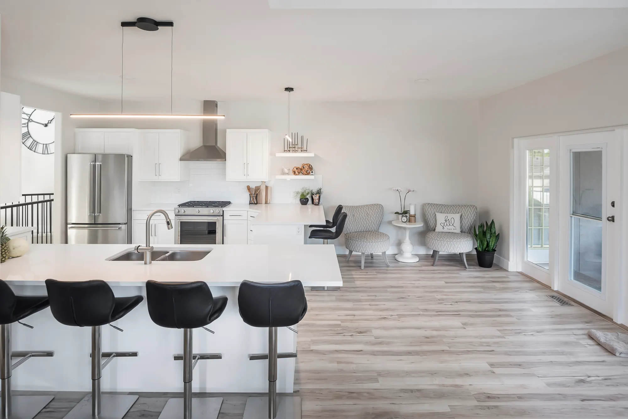 The new open kitchen with white cabinetry, a waterfall-edge quartz island, and warm wood floors