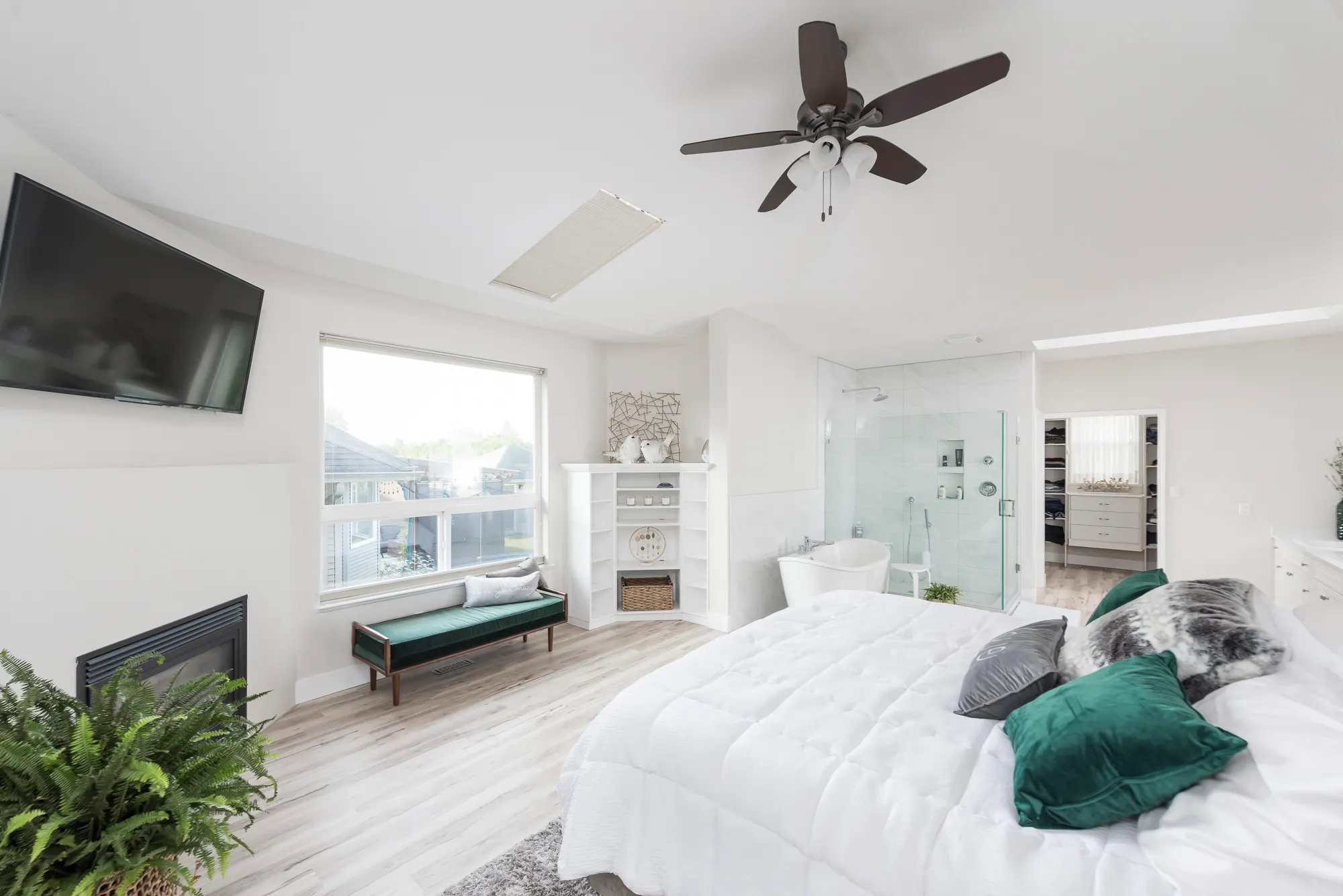 Primary bedroom with a fireplace, ceiling fan, and soft natural light