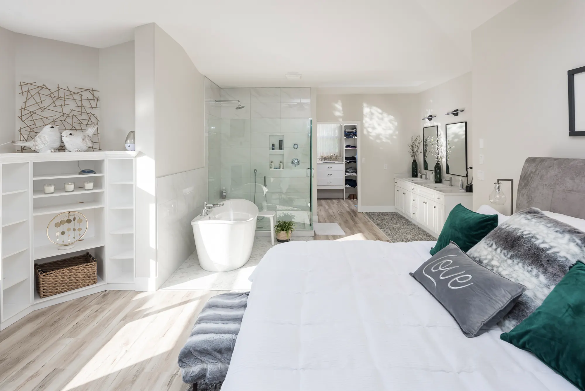 The rebuilt primary suite with a freestanding tub, frameless glass shower, and wood floors