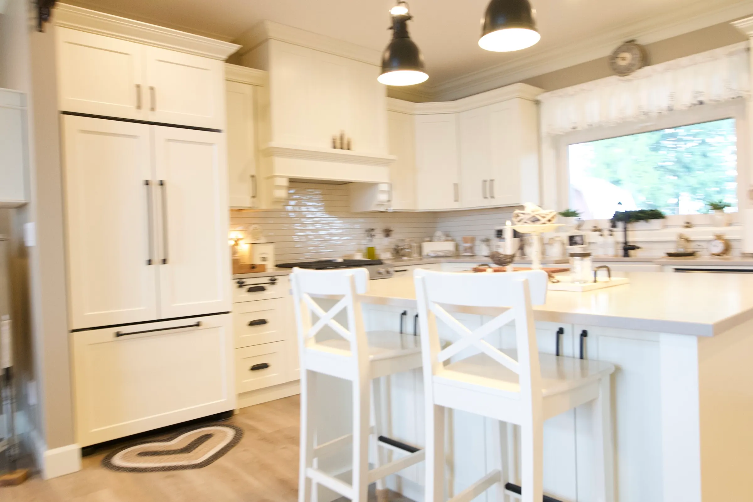 White shaker kitchen with a built-in refrigerator, subway backsplash, and warm wood floors