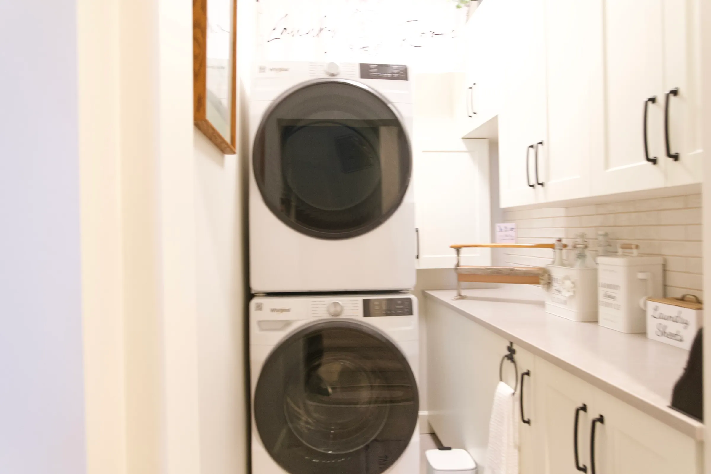 Bright farmhouse laundry room with a stacked washer and dryer and quartz folding counter