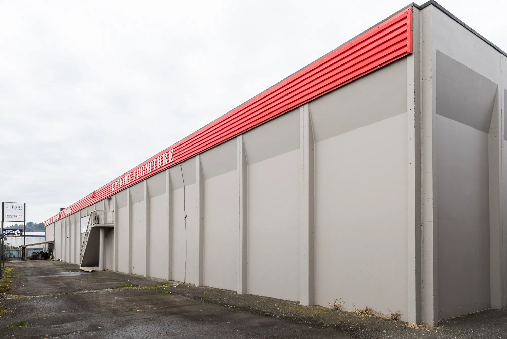 Freshly painted grey exterior wall with a red roofline band at GP Home Furniture