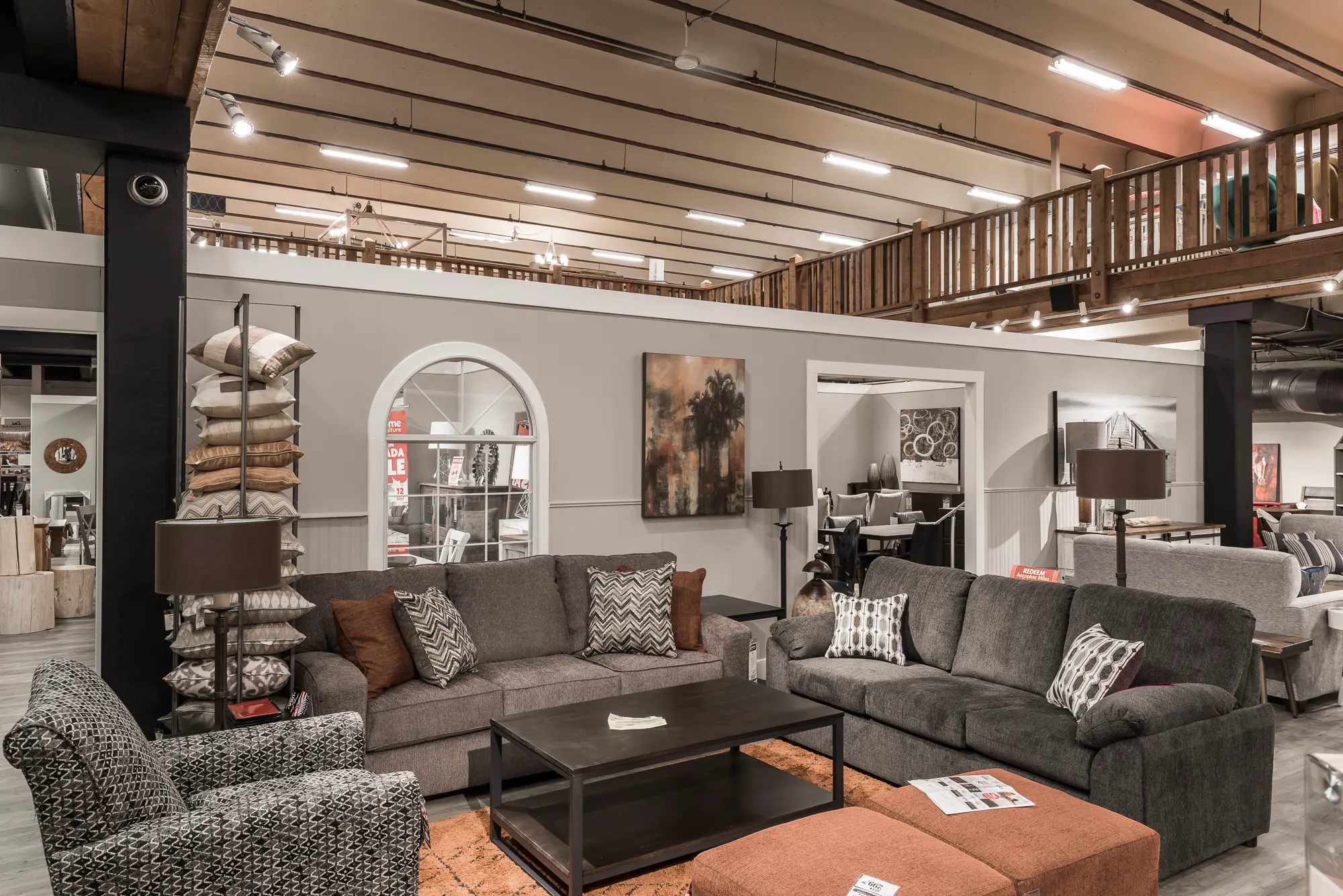 GP Home Furniture showroom with gallery walls, black ceilings, and a wood-railed mezzanine