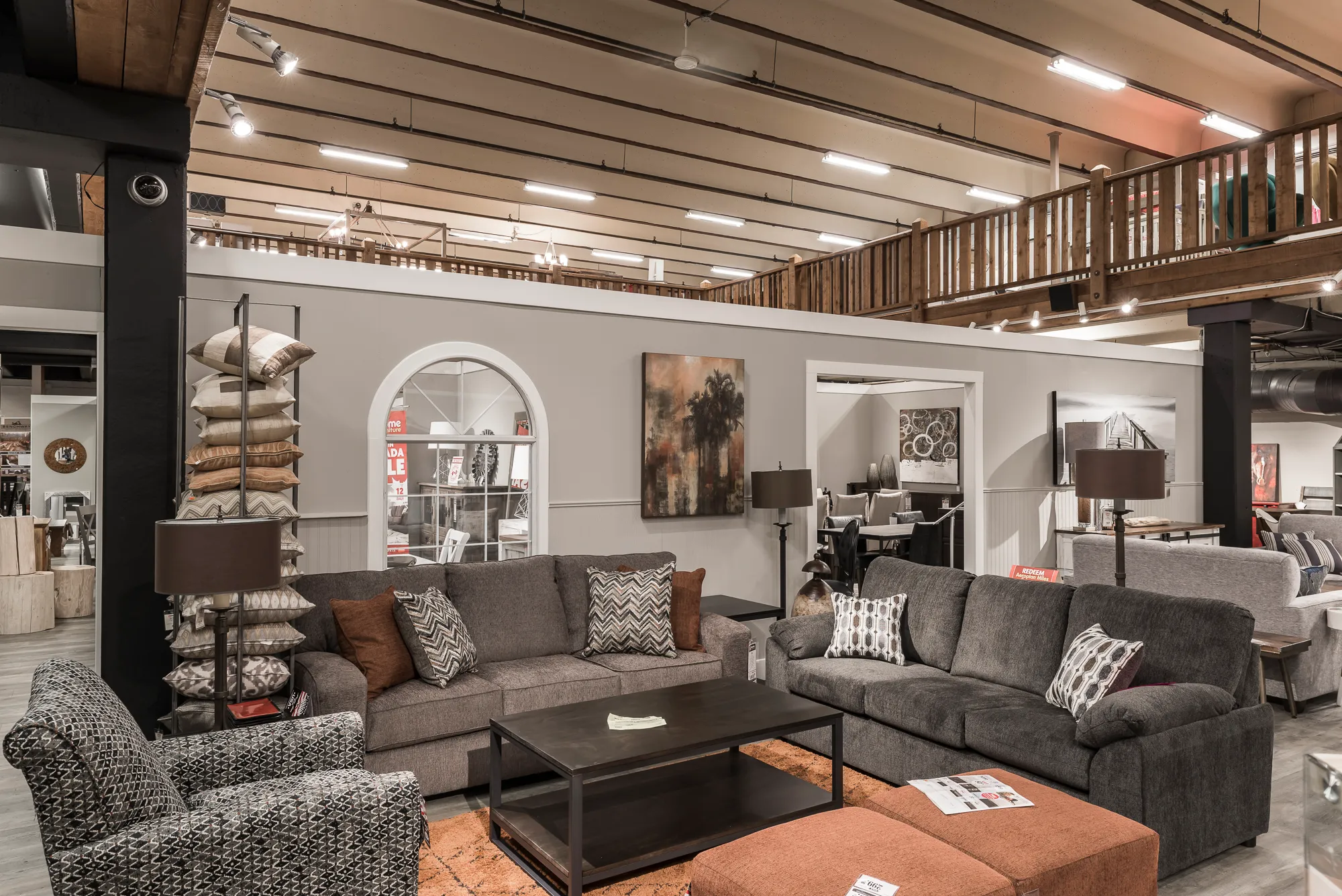 GP Home Furniture showroom with gallery walls, black ceilings, and a wood-railed mezzanine above