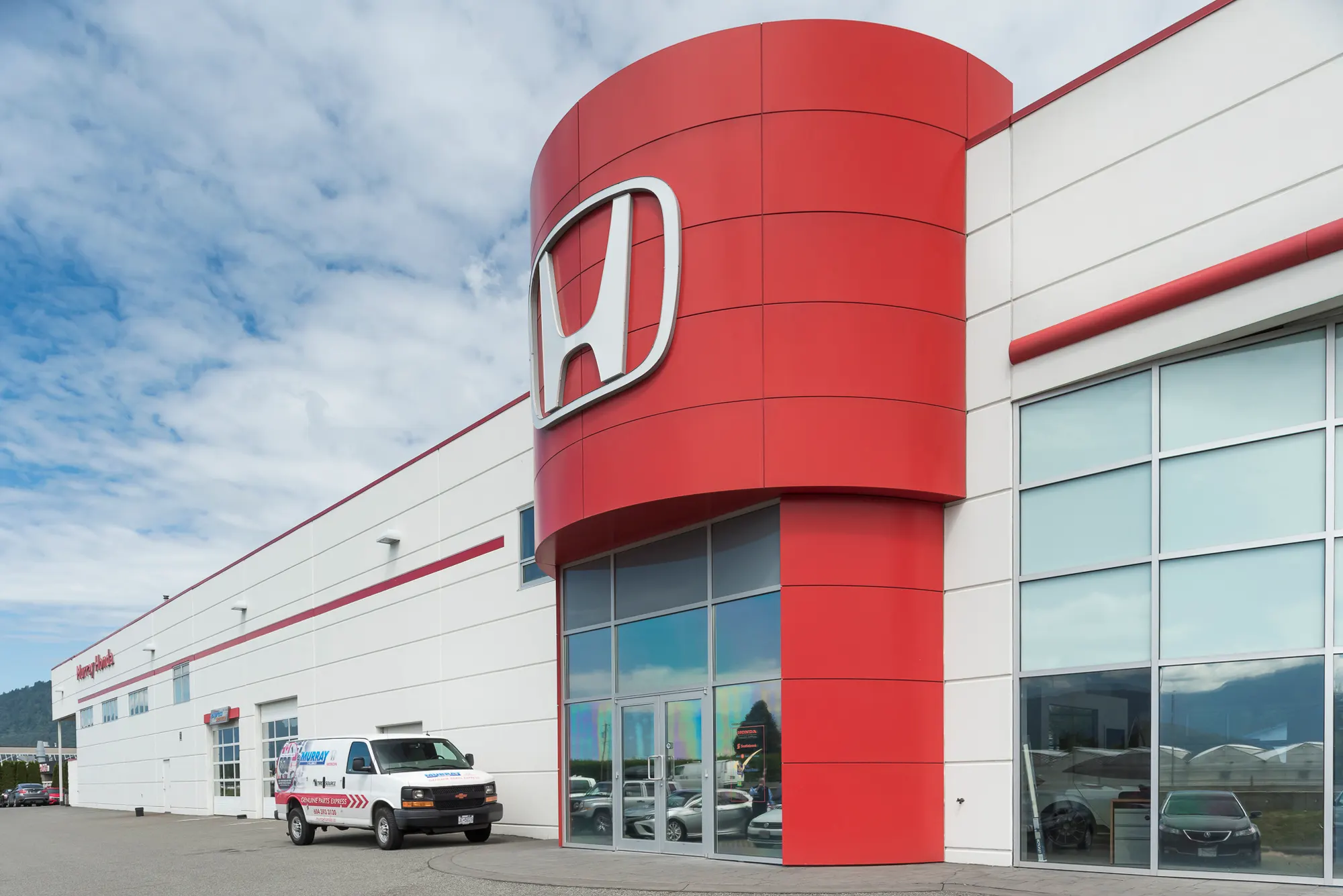 Red Honda brand tower rising above the white dealership exterior