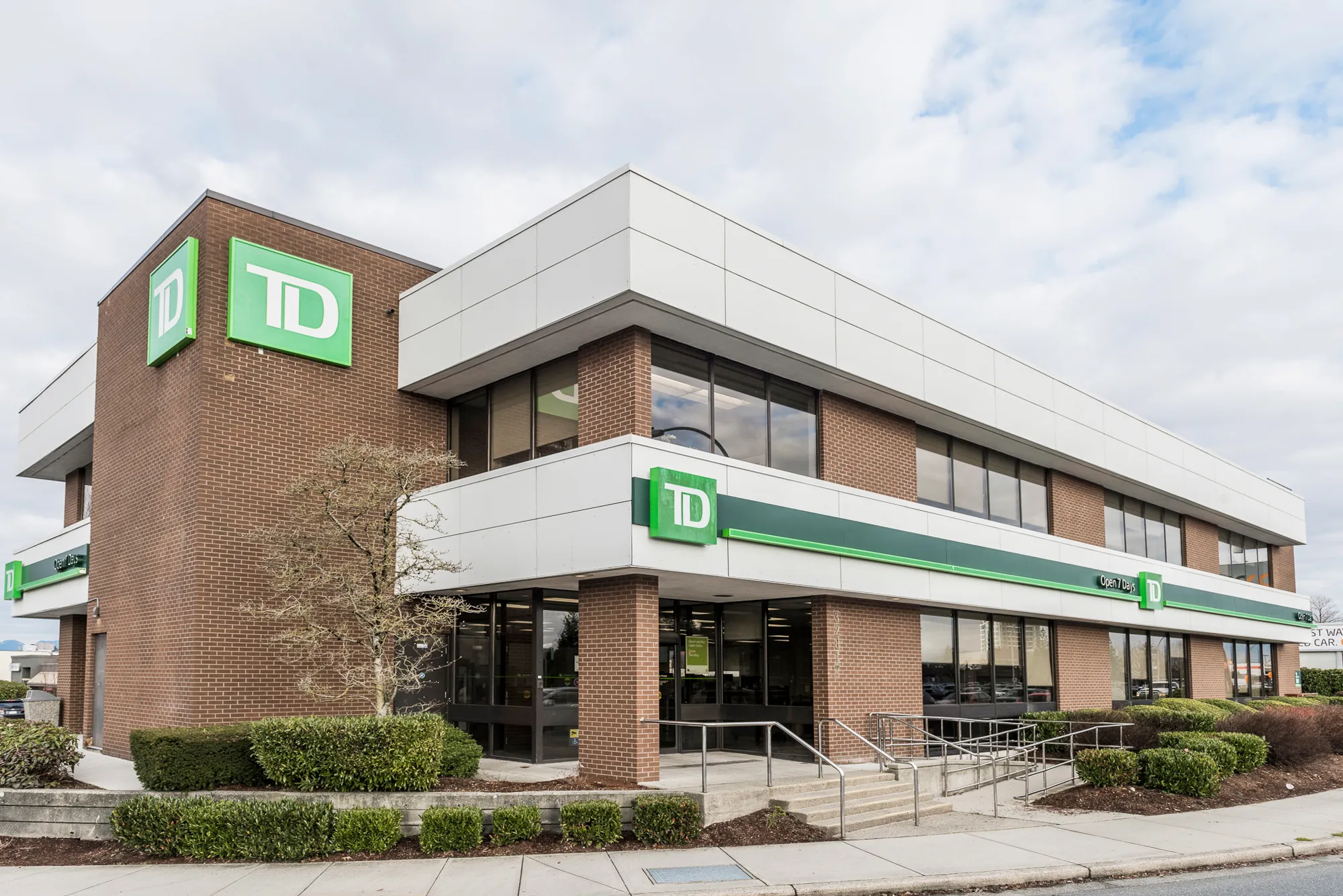 TD Bank branch exterior with white fascia bands over brown brick and the green TD corner sign