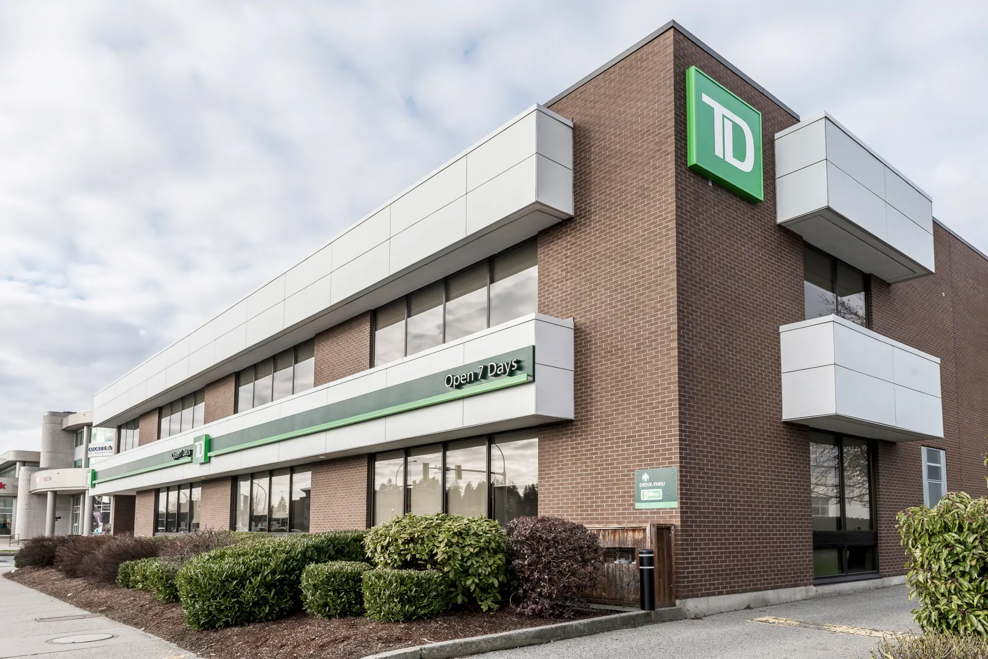 Long side elevation of the TD Bank branch with white fascia over brick and fresh landscaping