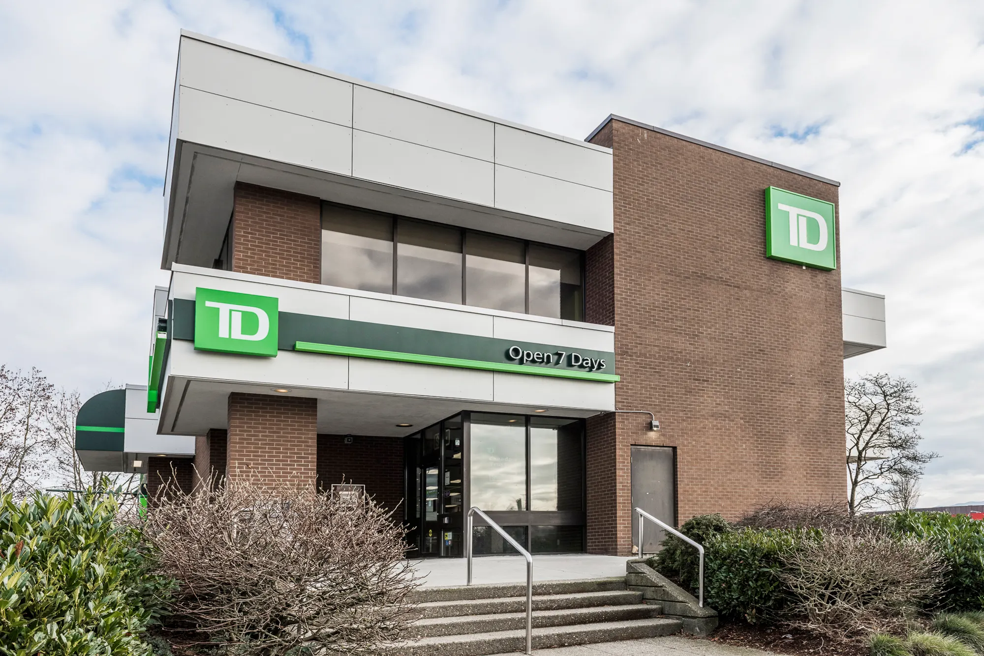 TD Bank branch entrance with steps, railings, and an Open 7 Days sign band
