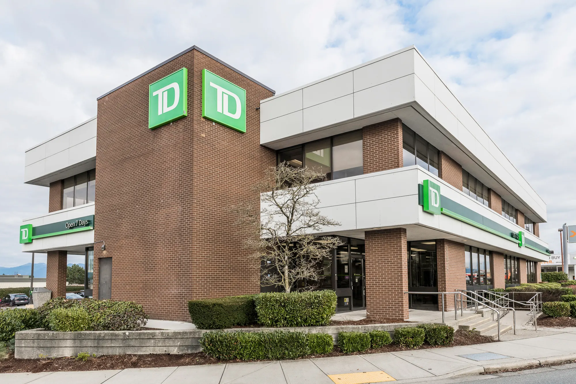 Corner tower of the TD Bank branch with the TD sign above white fascia bands and brick