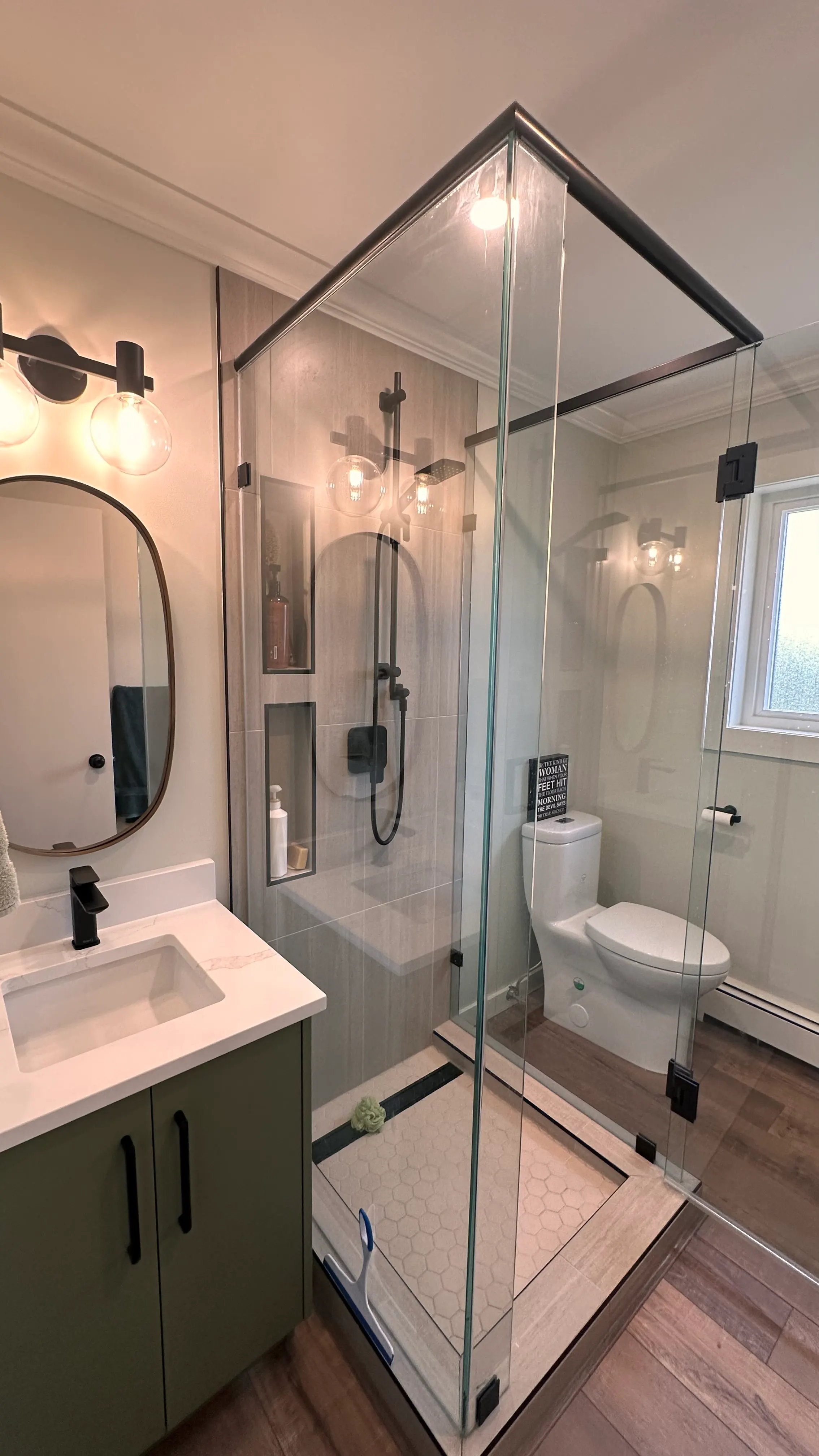 The rebuilt bathroom with a tiled glass walk-in shower, black fixtures, and a floating vanity