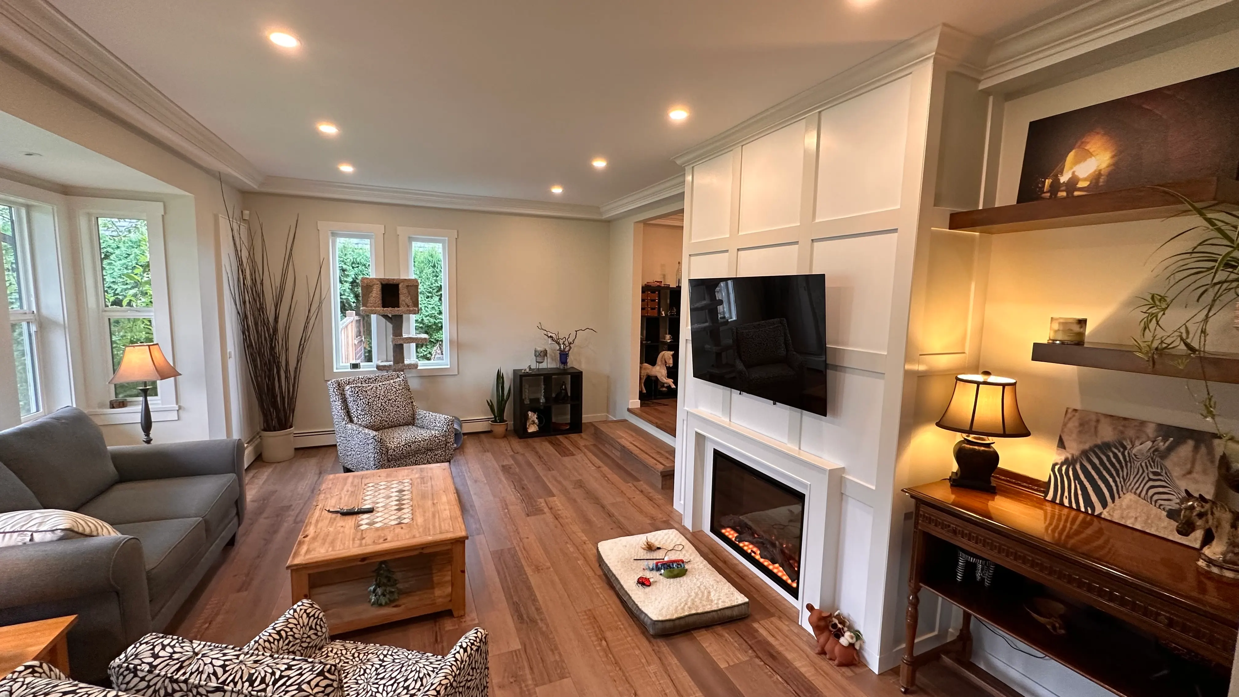 Living room with a white millwork fireplace wall, floating shelves, and wood floors after renovation