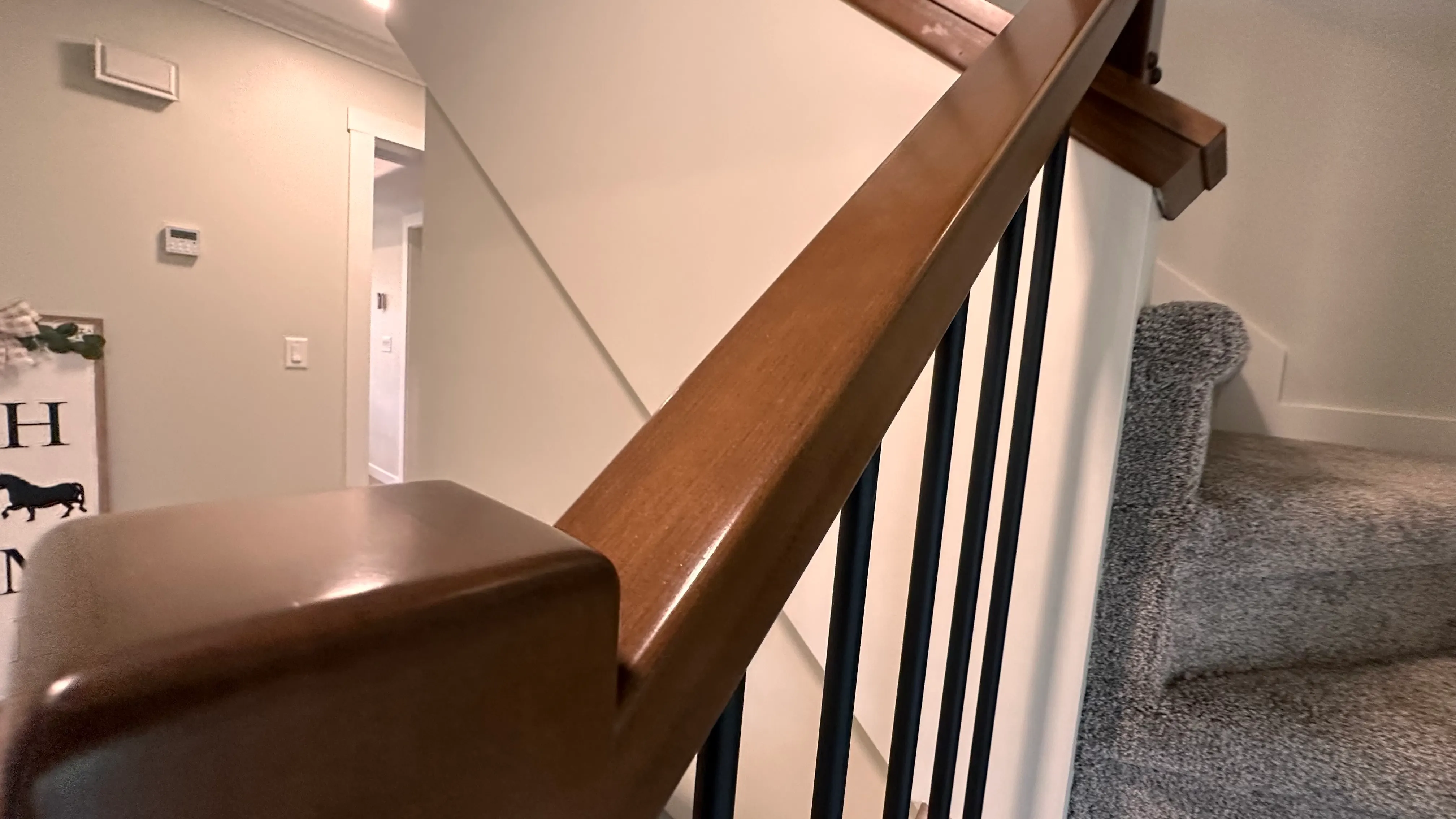 Staircase with a warm wood handrail and clean black metal spindles