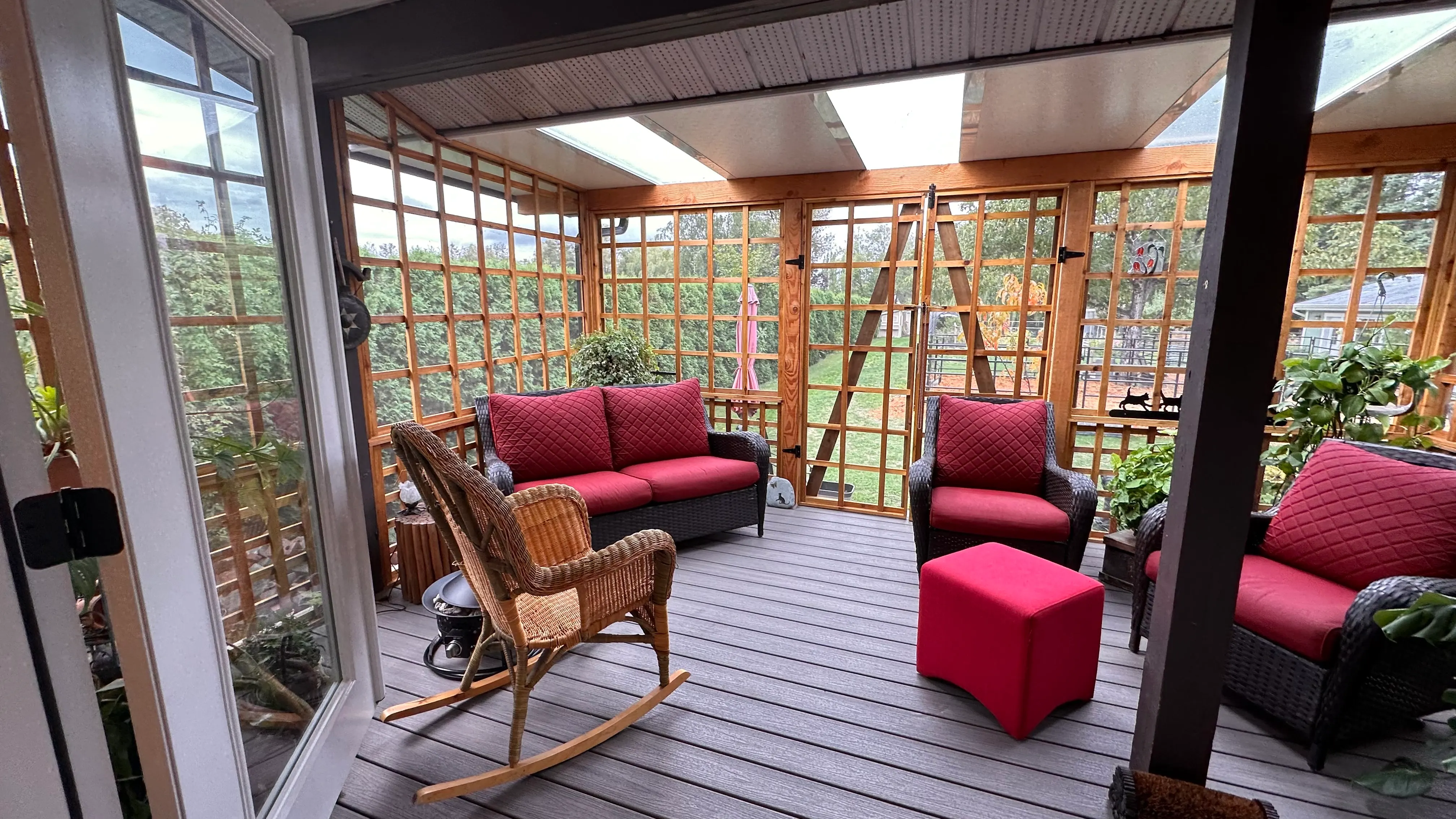 Bright sunroom with a glass roof, wood trellis walls, and comfortable seating