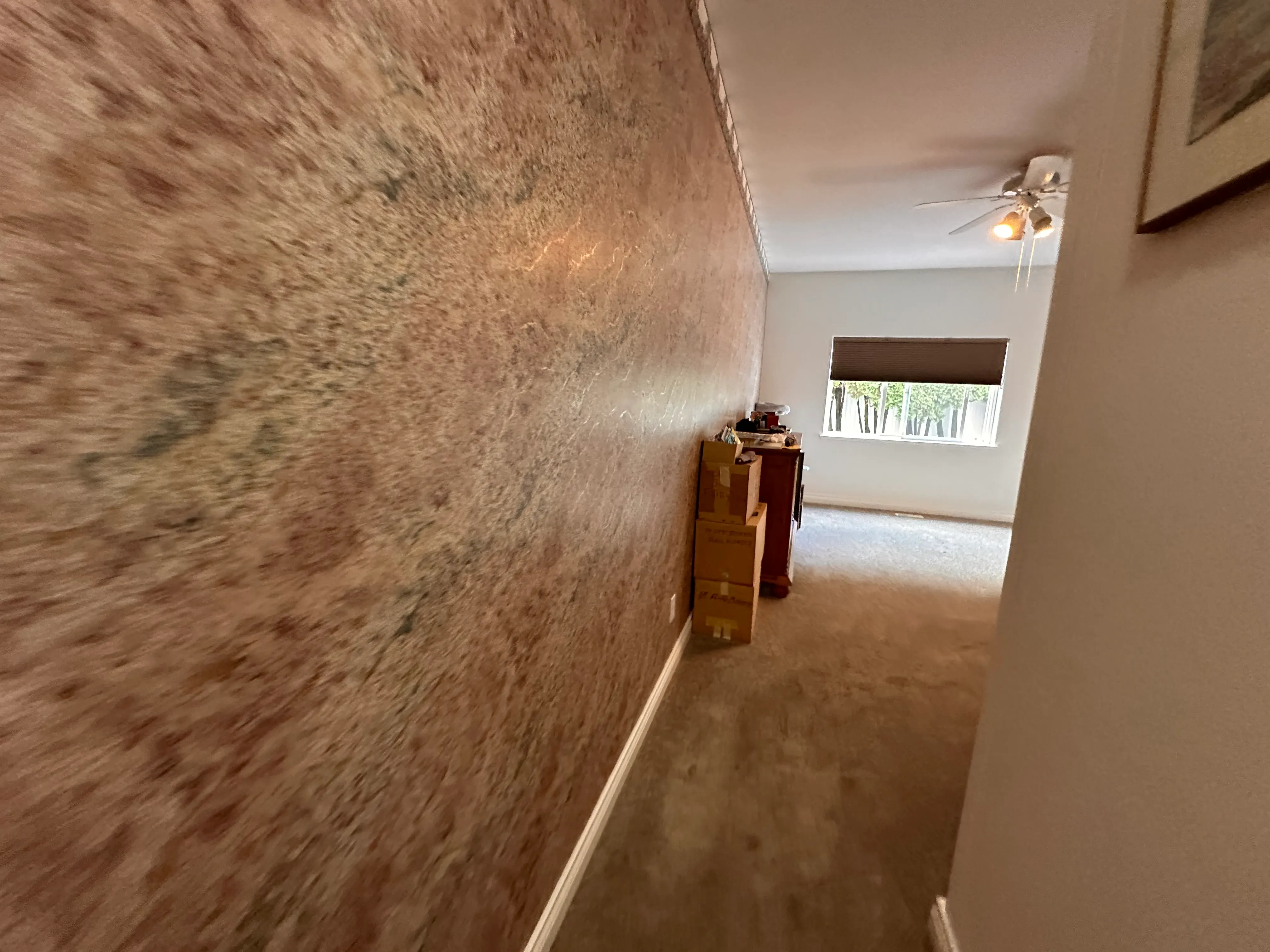 A hallway with dusty pink sponge-painted walls and wall-to-wall carpet