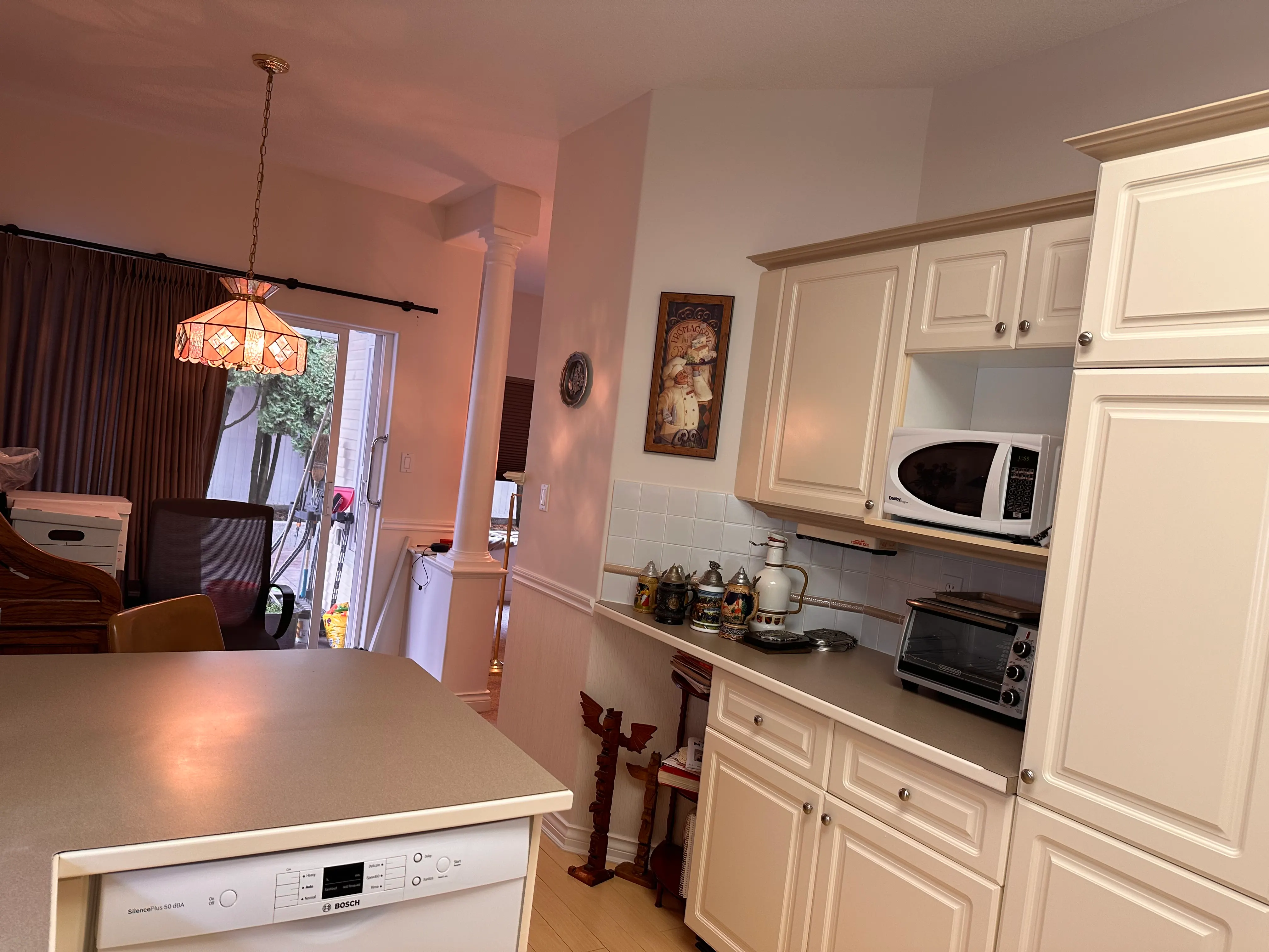The kitchen seen from the dining area, with older appliances and a peninsula