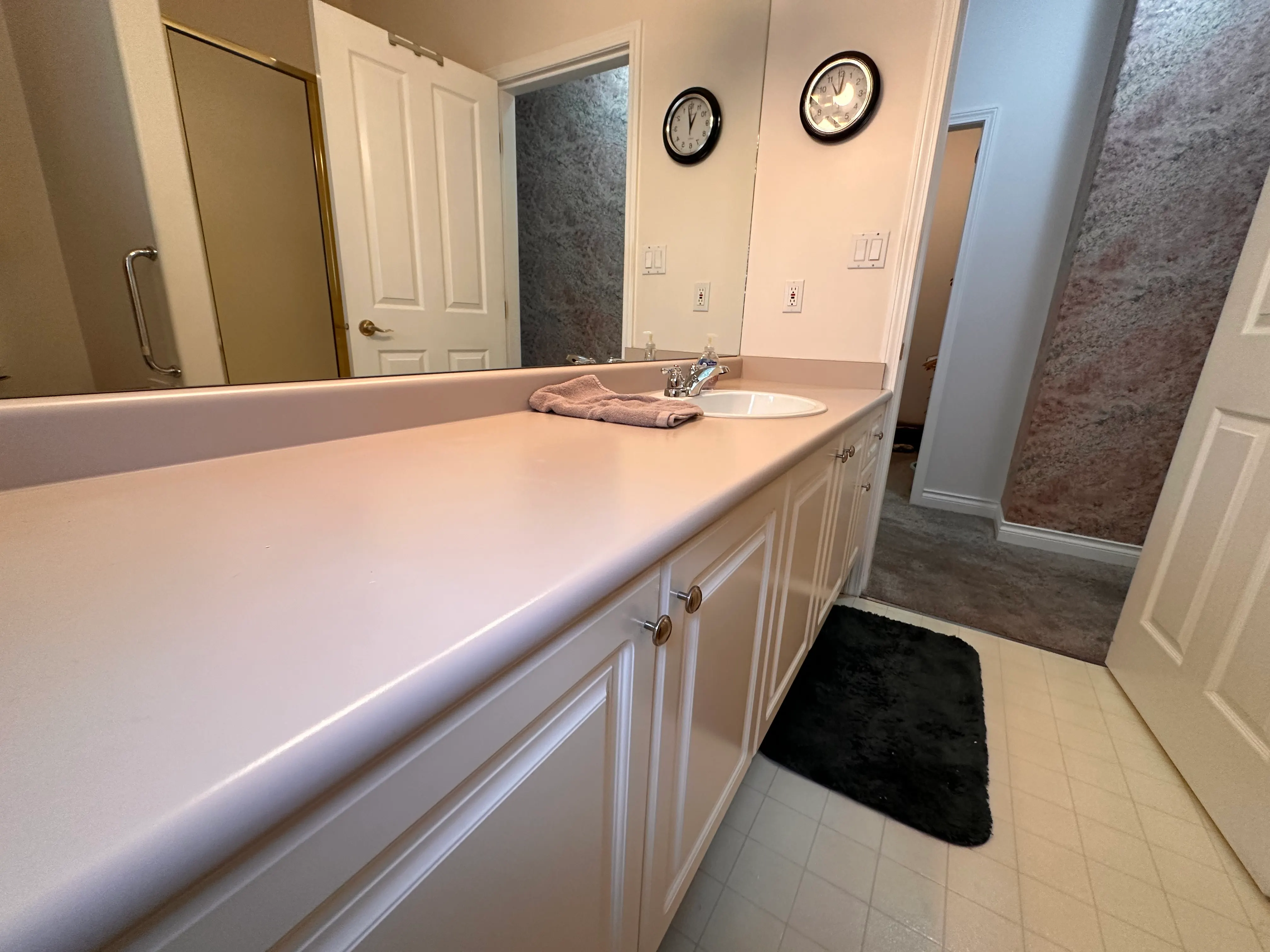 A cultured-marble vanity with a large mirror in the original bathroom