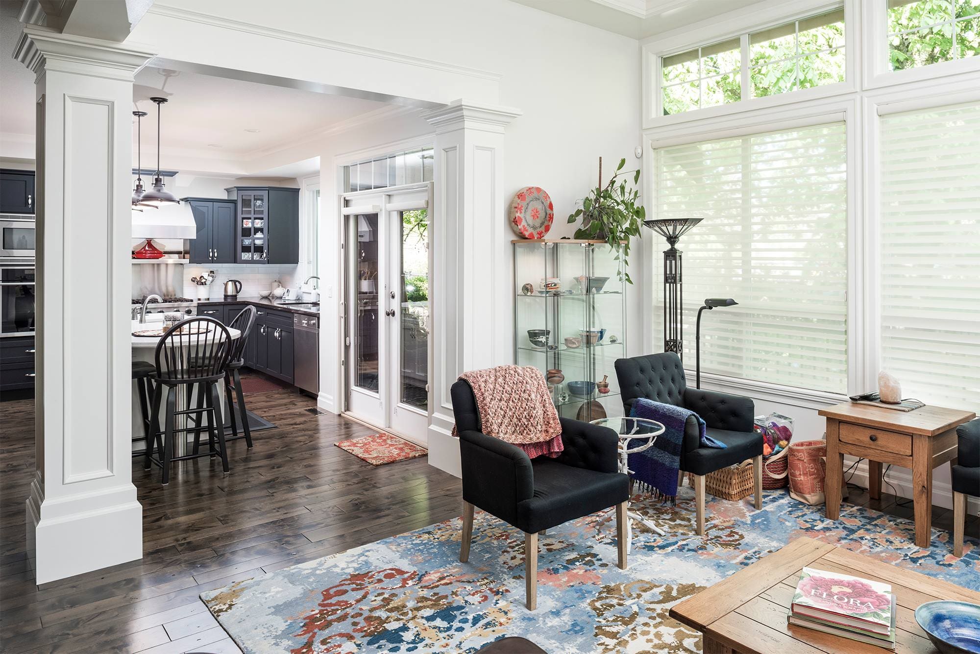 Open plan living room with tufted chairs colorful area rug and kitchen view Chilliwack BC
