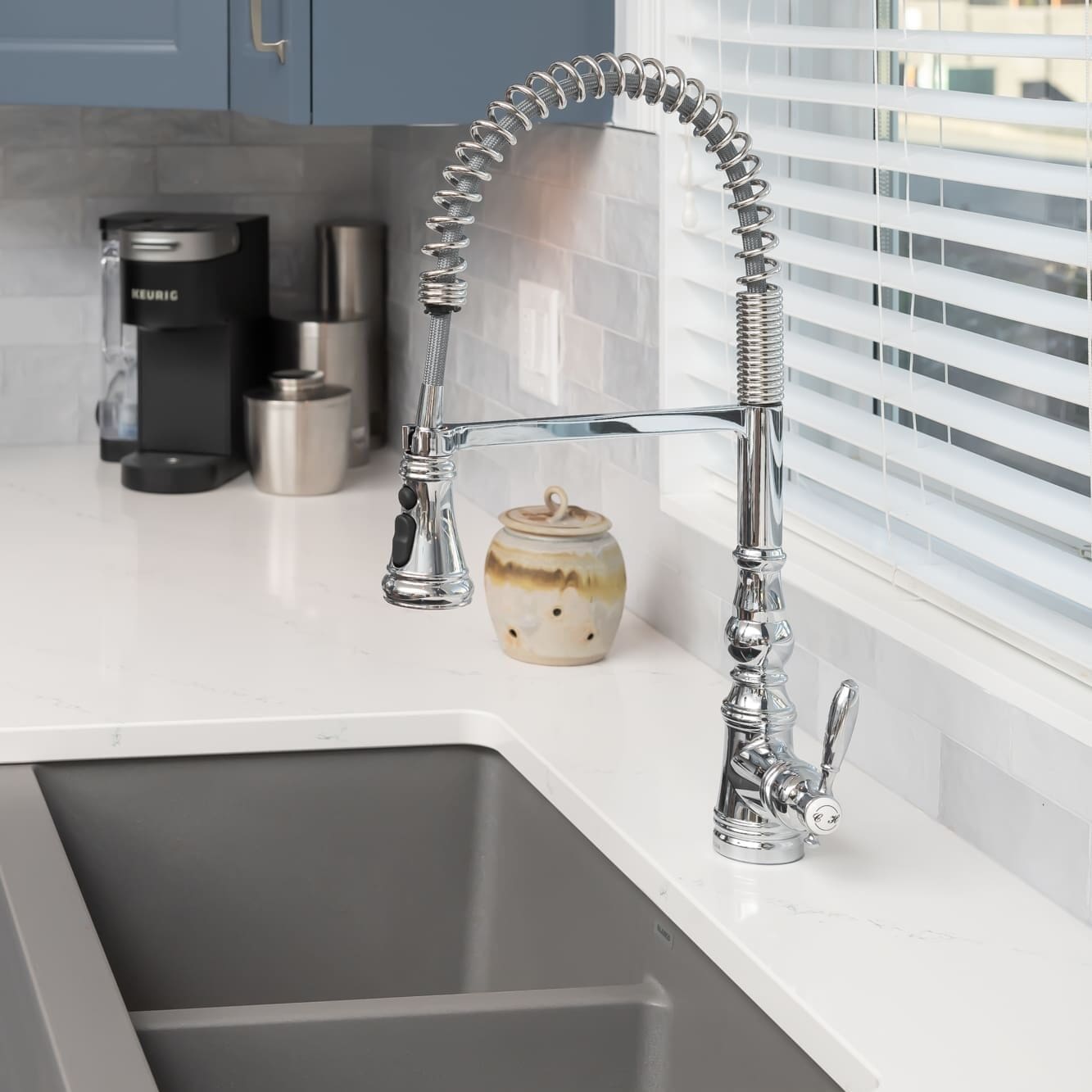 Professional spring-style chrome kitchen faucet with undermount sink, white quartz countertop, grey subway tile backsplash, and coffee station