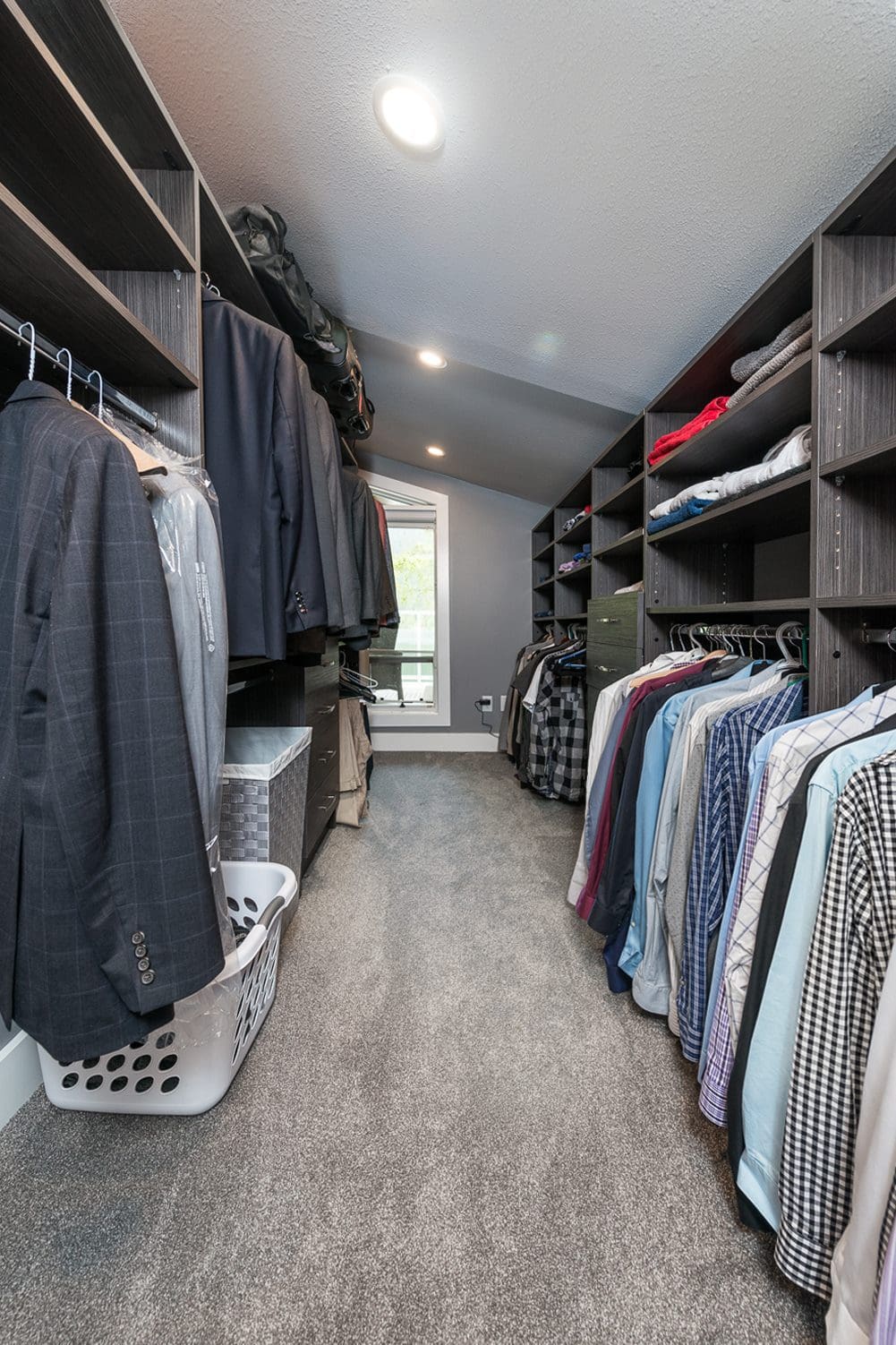 Large walk-in closet with dark wood organizer system and grey carpet Chilliwack BC
