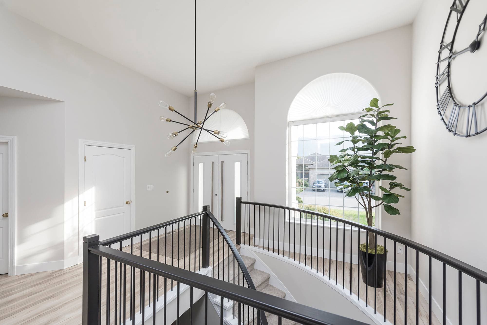 Upper landing with sputnik chandelier curved iron railing and arched window Chilliwack