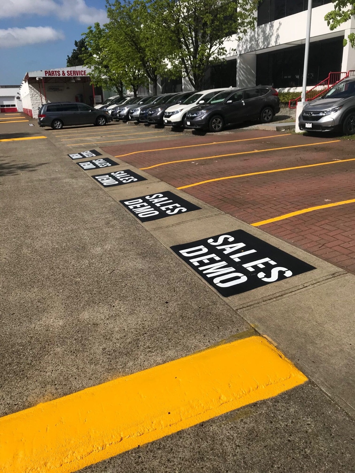 Commercial car dealership parking lot with freshly painted yellow line markings and Sales Demo stenciled parking spaces in the Fraser Valley