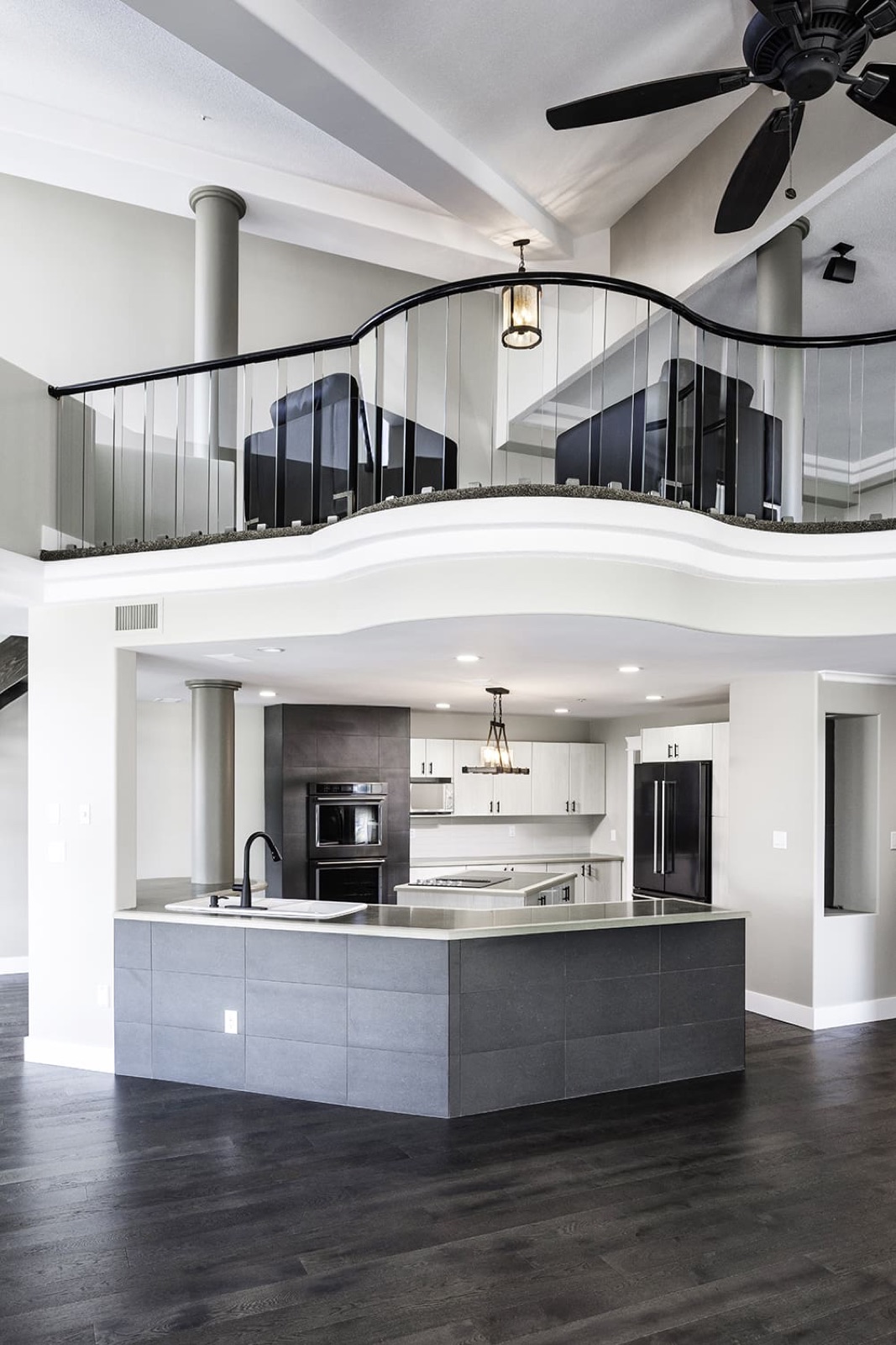 Luxury Chilliwack kitchen and loft with curved glass railing, modern cabinetry, and professionally painted finishes showcasing clean transitions and elevated design