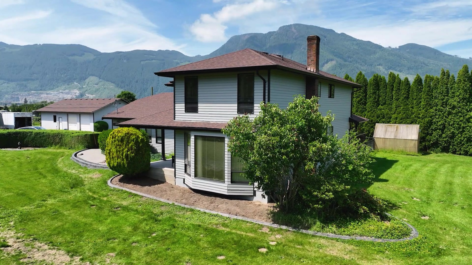 Home with fresh light-grey siding, crisp trim, and bold garage doors after an exterior repaint