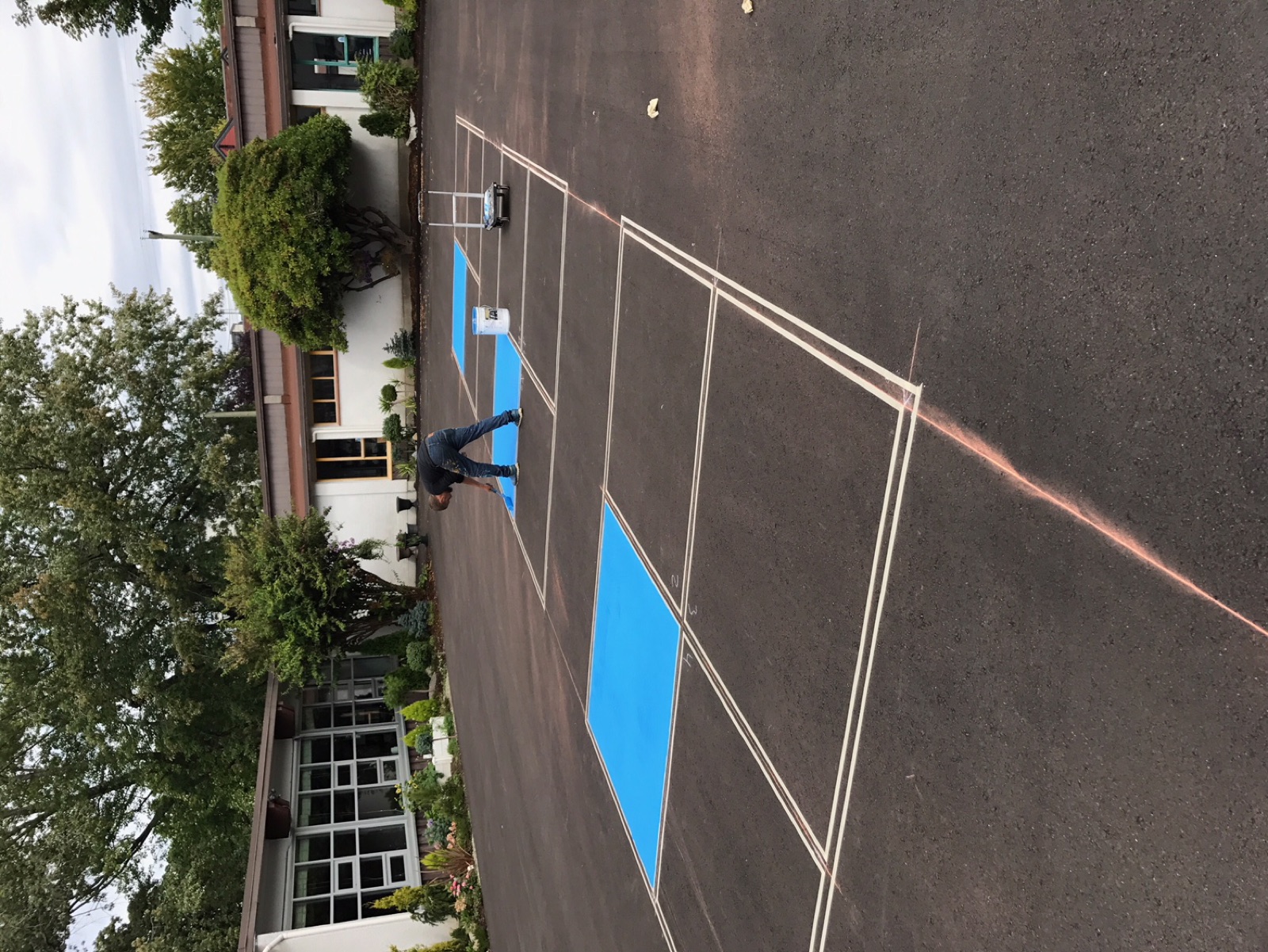 Line painting crew laying out fresh parking lot markings at a commercial property
