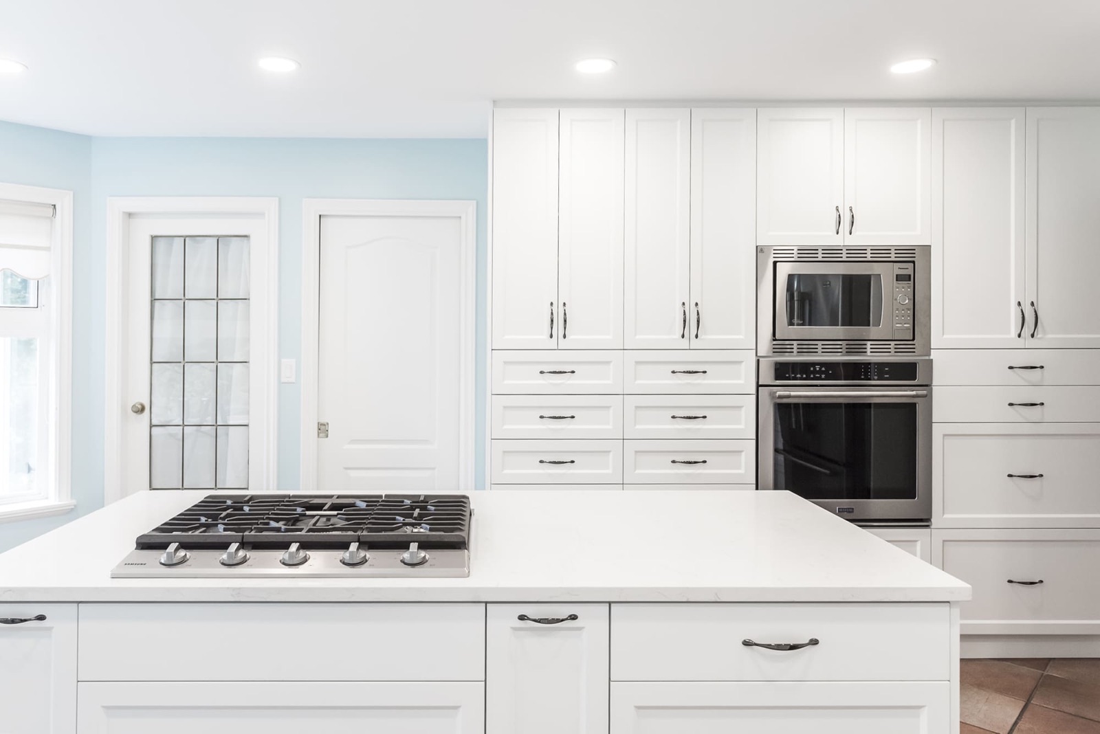 Modern white kitchen with clean lines and minimal clutter, featuring light cabinets and stainless steel appliances