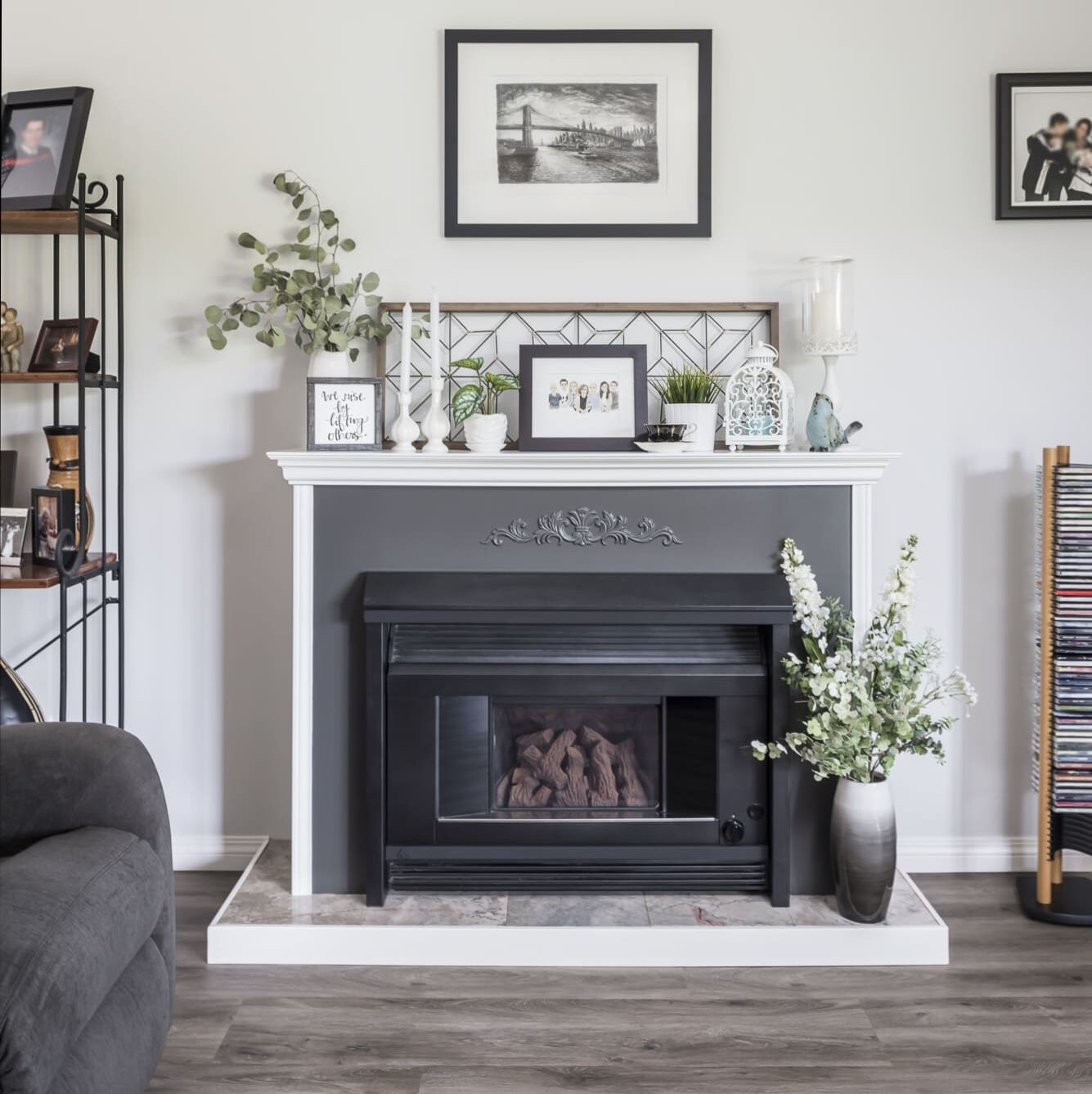 Modern fireplace with black and white mantle in Chilliwack home featuring satin-finish walls, decorative trim, and neutral-toned laminate flooring